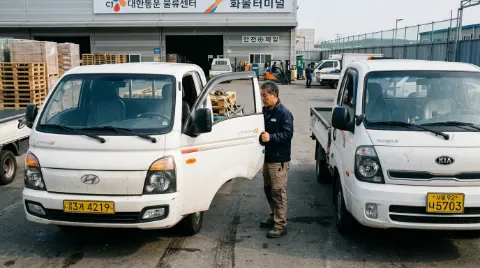 화물차 주차장에서 포터와 봉고 1톤 카고를 비교해보는 중년 예비 용달기사